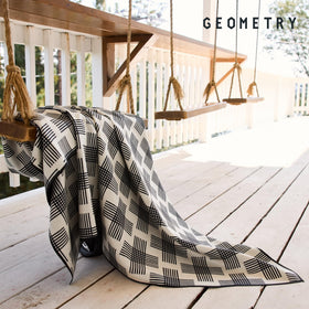 GEOMETRY Micro-Loop Beach Towel spread on sand beside waves for lounging.