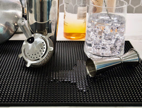 Highball & Chaser spill-containment bar mat prevents liquid spread on busy counters.