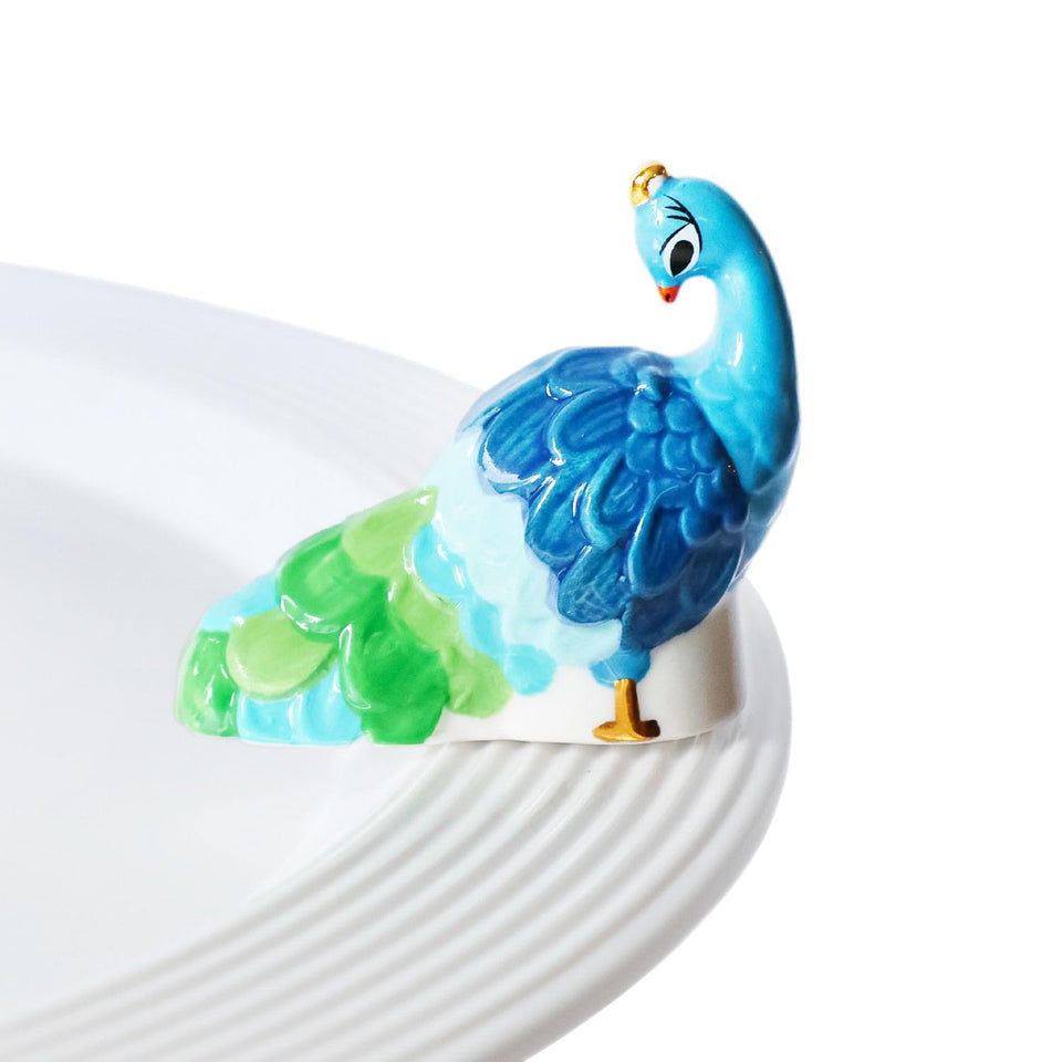 Nora Fleming Fancy Feathers Peacock mini on display adds vibrant color to any space.