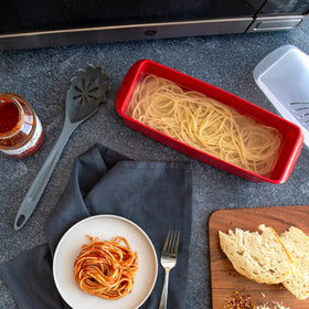 Nordic Ware microwave pasta cooker with vented lid, shows quick-drain capability.
