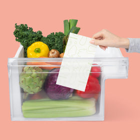 FreshPaper sheets with assorted produce in a clamshell keeping greens fresh.
